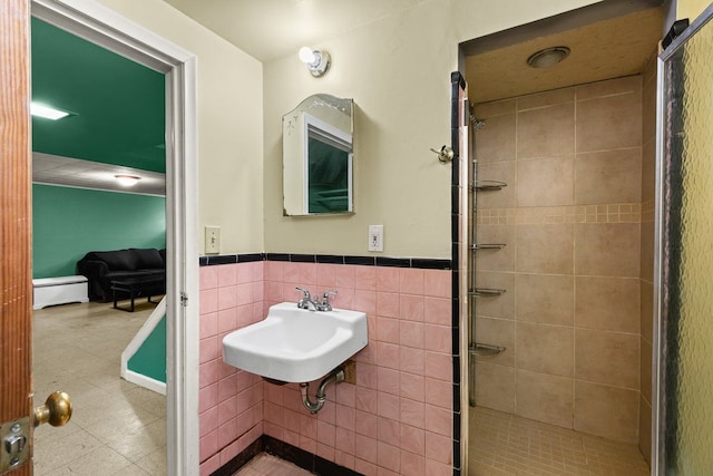 full bathroom with a wainscoted wall, a stall shower, a sink, and tile walls