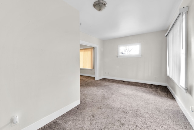 carpeted spare room with visible vents and baseboards