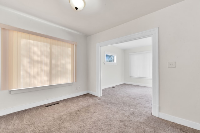 carpeted empty room with visible vents and baseboards