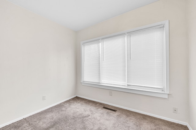 carpeted spare room featuring visible vents and baseboards