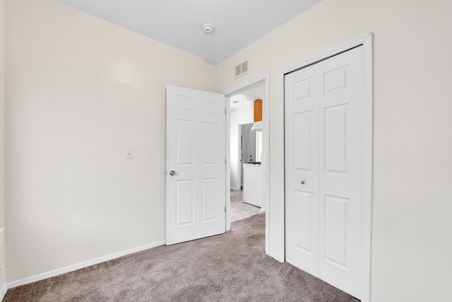 unfurnished bedroom featuring carpet floors, a closet, visible vents, and baseboards