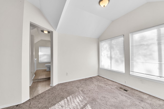 carpeted empty room with lofted ceiling, baseboards, and visible vents