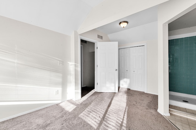 unfurnished bedroom featuring carpet floors, lofted ceiling, a closet, visible vents, and baseboards