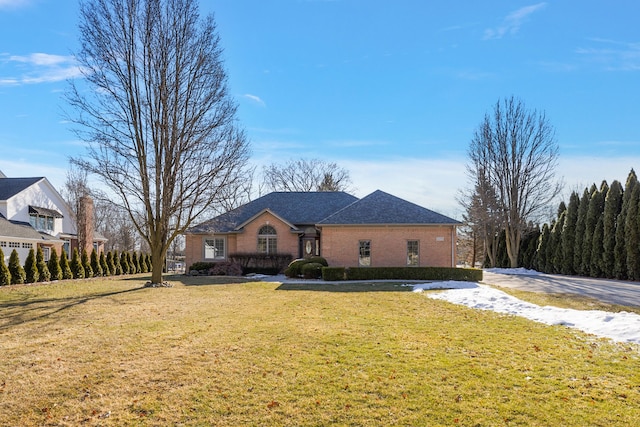 view of front of home featuring a front lawn, a shingled roof, and brick siding