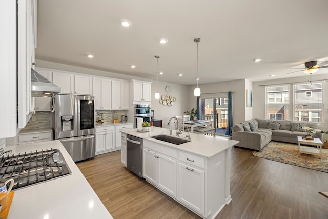 kitchen with appliances with stainless steel finishes, wood finished floors, light countertops, and a sink