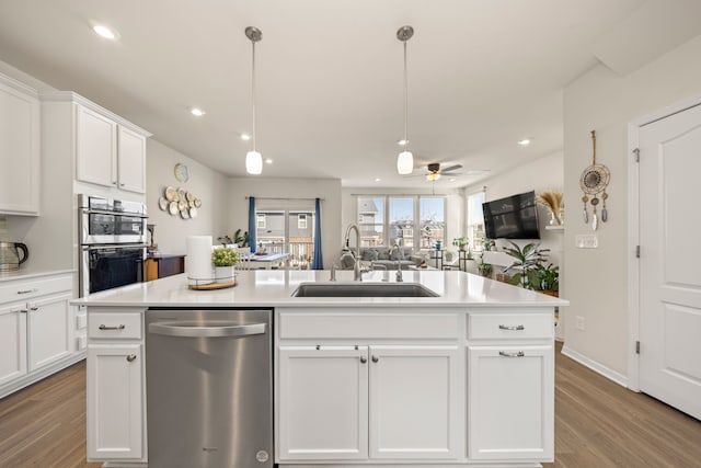 kitchen with light countertops, light wood-style flooring, white cabinets, stainless steel appliances, and a sink