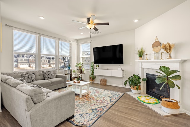 living area featuring a fireplace, recessed lighting, wood finished floors, and baseboards