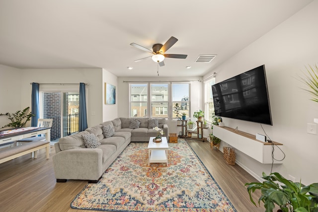 living area featuring visible vents, baseboards, ceiling fan, and wood finished floors