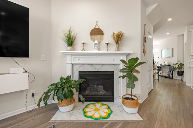 living area with recessed lighting, a premium fireplace, baseboards, and wood finished floors