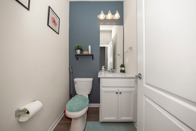 bathroom featuring toilet, vanity, baseboards, and wood finished floors