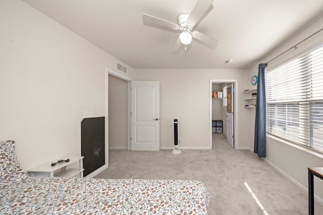 carpeted bedroom with visible vents, a walk in closet, a ceiling fan, a closet, and baseboards