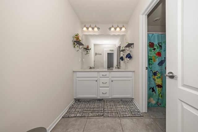 full bathroom featuring tile patterned floors, double vanity, baseboards, and a sink