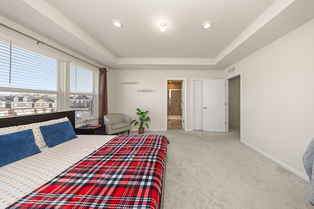 carpeted bedroom with a tray ceiling, baseboards, visible vents, and ensuite bath