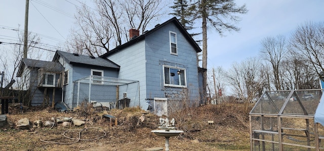 view of side of home featuring an exterior structure, a chimney, and an outdoor structure