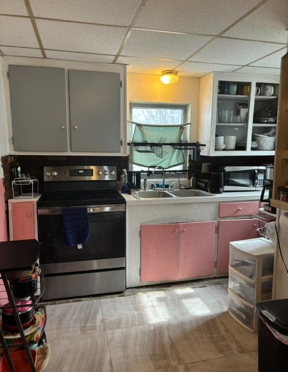 kitchen with a sink, light countertops, a paneled ceiling, and stainless steel appliances