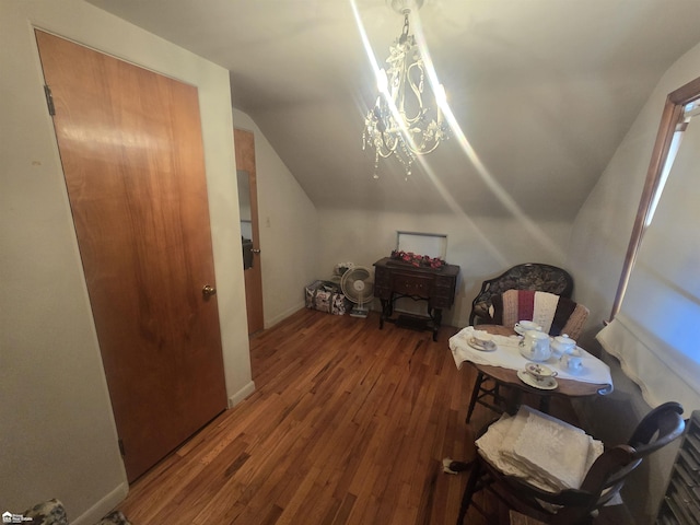 interior space featuring lofted ceiling, baseboards, a notable chandelier, and hardwood / wood-style floors