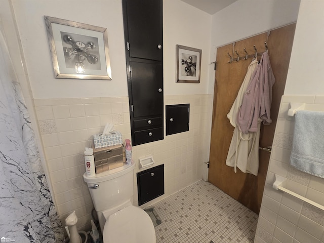 bathroom with toilet, wainscoting, a shower with shower curtain, and tile walls