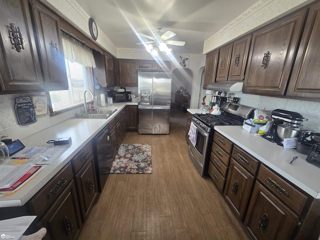 kitchen featuring decorative backsplash, wood finished floors, under cabinet range hood, black appliances, and a sink