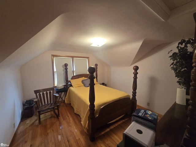 bedroom with vaulted ceiling and wood finished floors