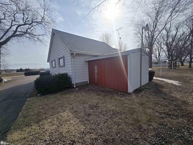 view of property exterior with roof with shingles and an outdoor structure