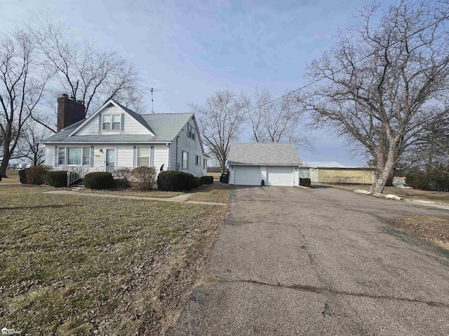 view of front of home with an outdoor structure, a chimney, and a detached garage