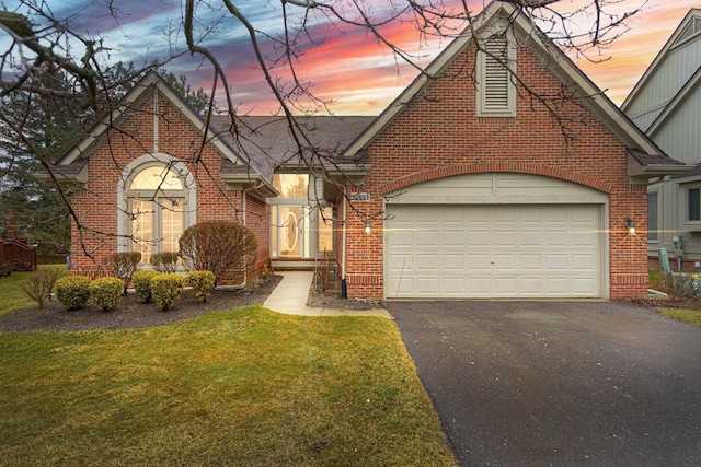 view of front of property featuring driveway, a garage, a lawn, roof with shingles, and brick siding