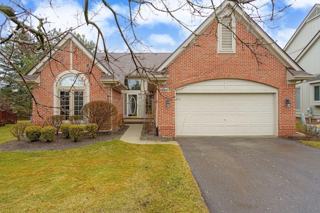 view of front of house featuring brick siding, aphalt driveway, roof with shingles, an attached garage, and a front yard