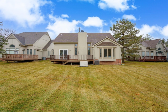 rear view of property featuring a lawn, a chimney, and a wooden deck