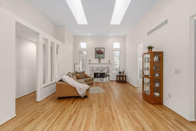 sitting room featuring light wood-type flooring, a skylight, a fireplace, and visible vents