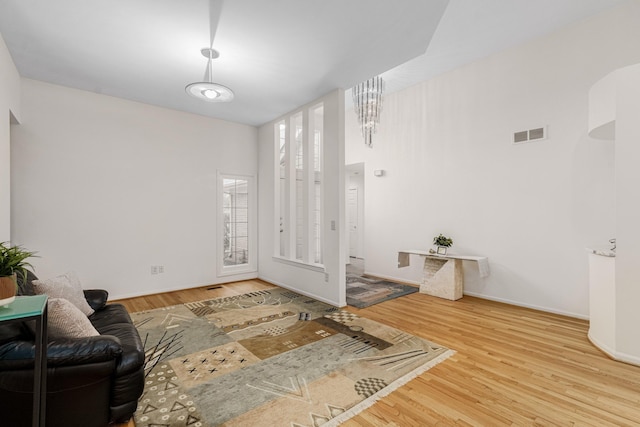 living area featuring baseboards, visible vents, and wood finished floors