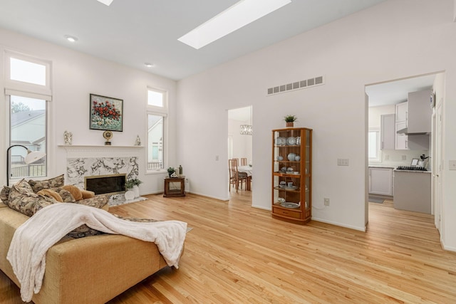 living room featuring a skylight, a fireplace, visible vents, a healthy amount of sunlight, and light wood-style floors