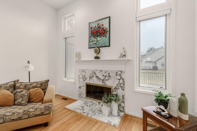 living area featuring wood finished floors, visible vents, baseboards, and a premium fireplace