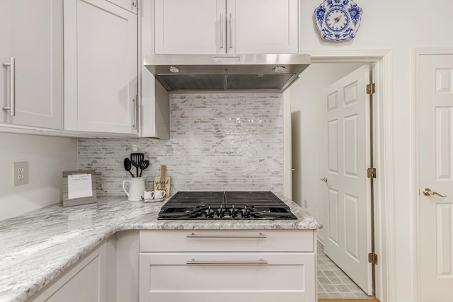 kitchen with black gas stovetop, decorative backsplash, white cabinets, and under cabinet range hood