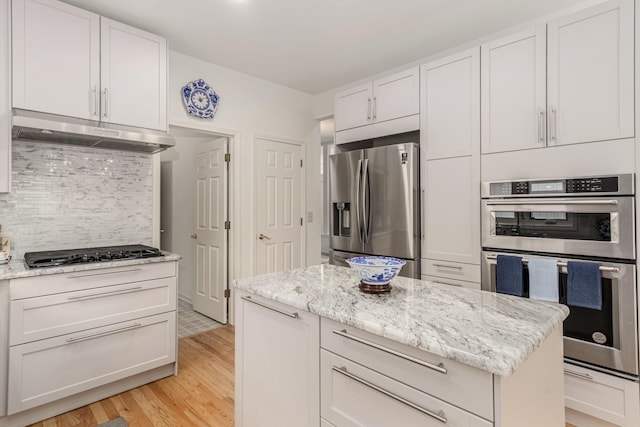 kitchen with tasteful backsplash, light wood-style floors, stainless steel appliances, under cabinet range hood, and white cabinetry