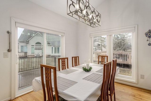 dining room featuring baseboards, light wood-style flooring, and an inviting chandelier