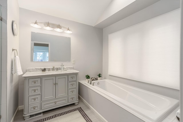 bathroom featuring vaulted ceiling, a garden tub, and vanity