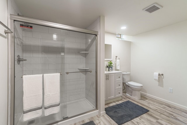 full bath with toilet, wood finished floors, vanity, visible vents, and a stall shower