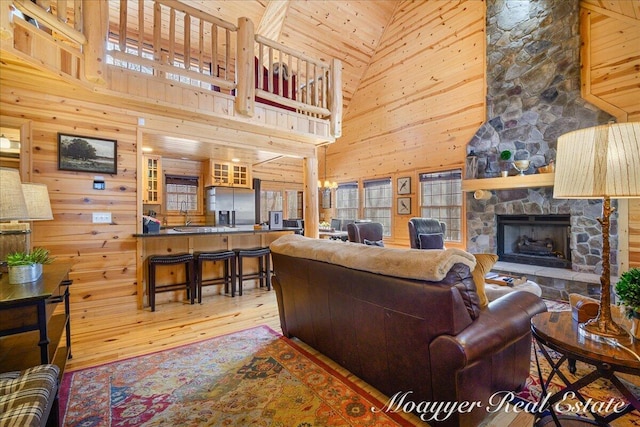 living room featuring wood-type flooring, wooden walls, and a stone fireplace