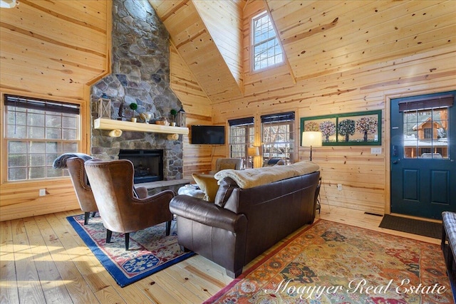 living area featuring wood-type flooring, a healthy amount of sunlight, a fireplace, and wooden walls