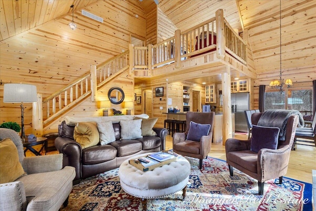 living room featuring stairway, an inviting chandelier, wood walls, wood finished floors, and wooden ceiling