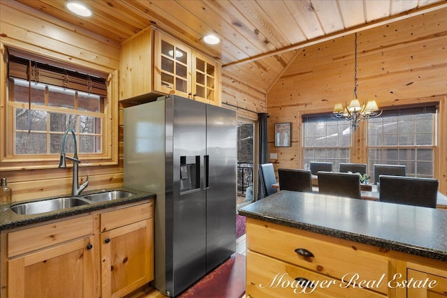 kitchen featuring wood ceiling, wooden walls, stainless steel refrigerator with ice dispenser, and a sink