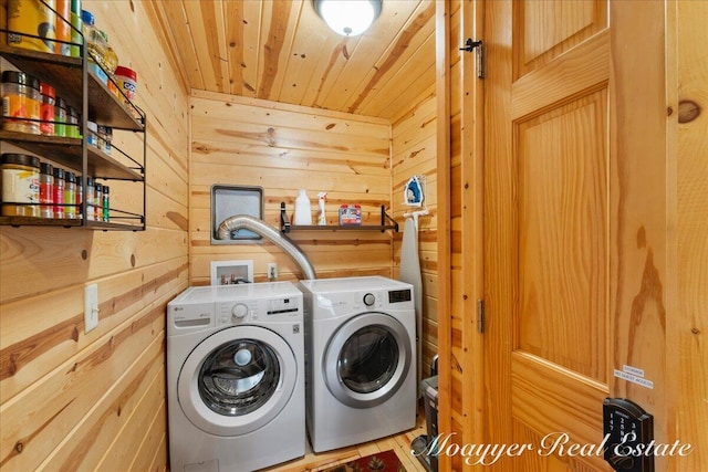 clothes washing area with wooden ceiling, laundry area, wooden walls, and washer and clothes dryer