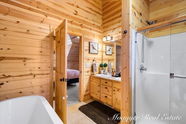 ensuite bathroom featuring wooden walls, a freestanding bath, tile patterned floors, double vanity, and a stall shower