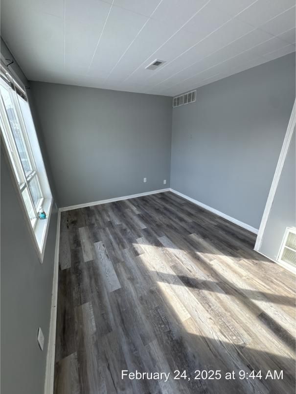 empty room with visible vents and dark wood-type flooring