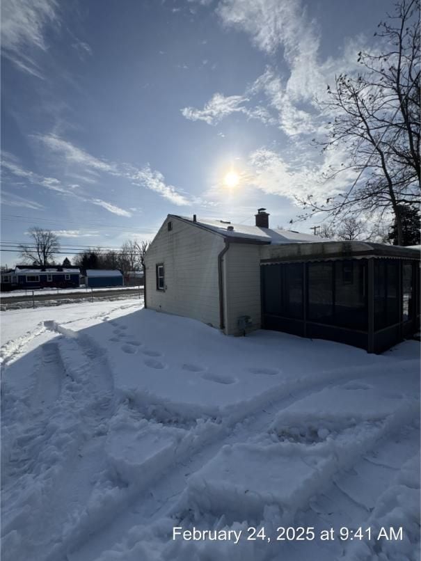 snow covered property featuring a sunroom