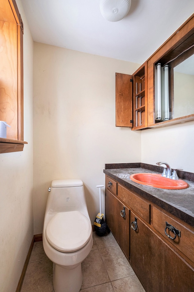 half bath featuring baseboards, vanity, toilet, and tile patterned floors