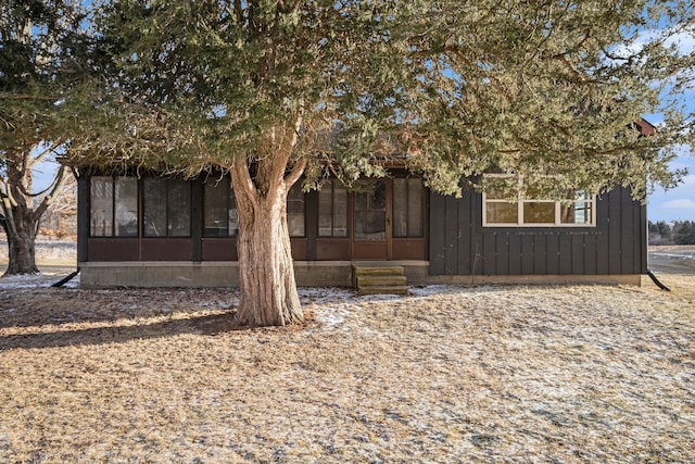 view of front of house with entry steps, board and batten siding, and a sunroom