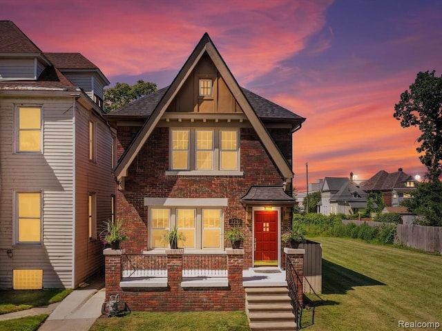 view of front facade featuring brick siding, a front lawn, and roof with shingles