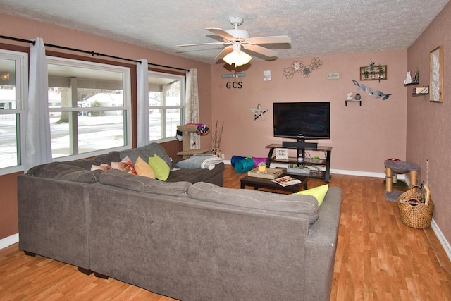 living area with a textured ceiling, ceiling fan, wood finished floors, and baseboards