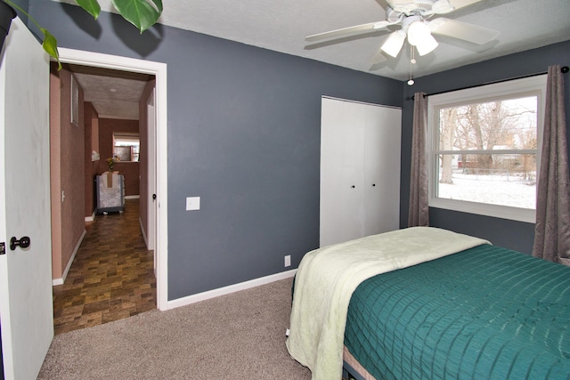 bedroom featuring ceiling fan, a closet, baseboards, and carpet flooring